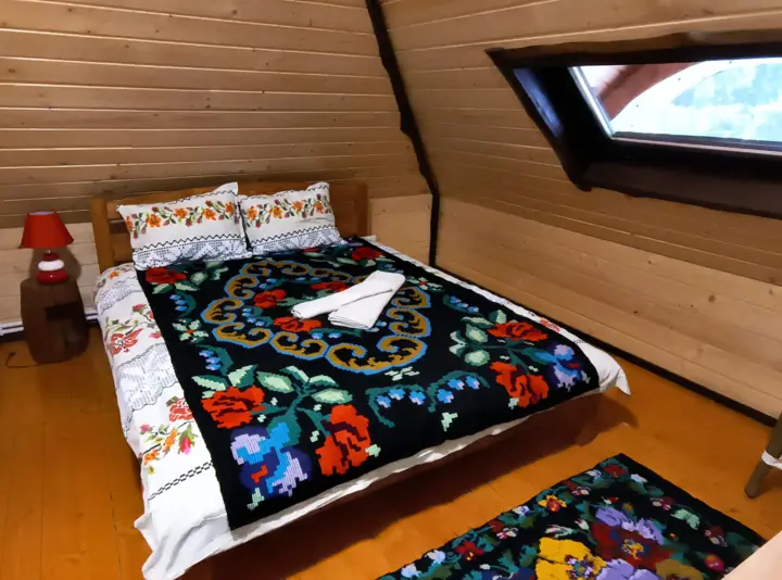 Dormitor la mansardă cu pat matrimonial și cuvertură brodată