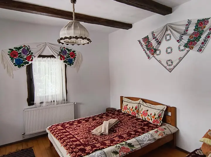 Dormitor la parter cu pat matrimonial și lenjerie tradițională