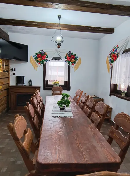 Sufragerie cu masă mare din lemn masiv și decor tradițional bucovinean